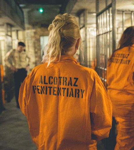 Inmate customers wearing orange jumpsuits at Alcotraz - immersive prison bar.